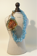 Collar aguamarina flor terracota — editorial fondo crema